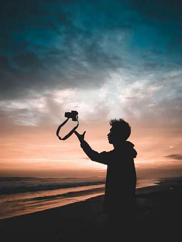 Young photographer throwing camera on the beach