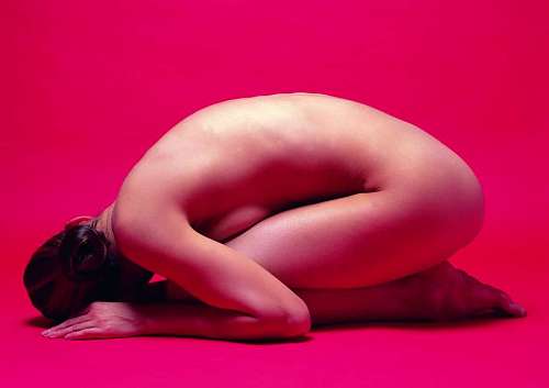 slim naked woman lying on red background
