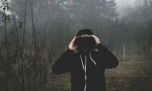 hooded man using VR with a swamp in the background