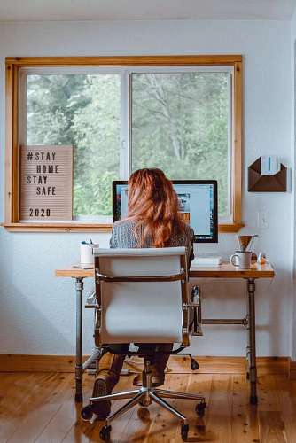 view from behind of a red-haired woman using her computer at the desk