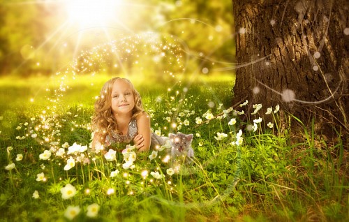 Little girl lying in the forest next to her little cat