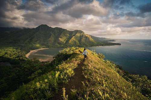 Woman walking on top of a mountain in front of the sea