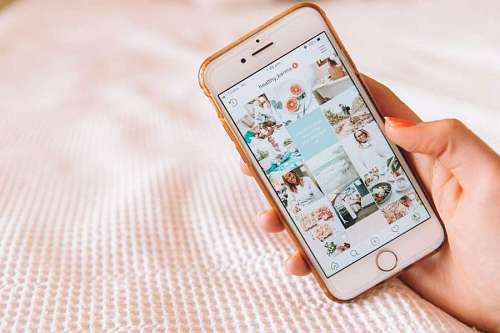 woman holding her cellphone on the bed