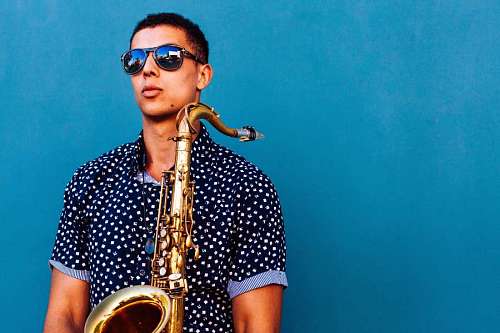 man  holding saxophone with light blue background