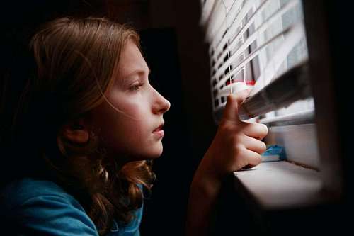 little girl peeking through the blind