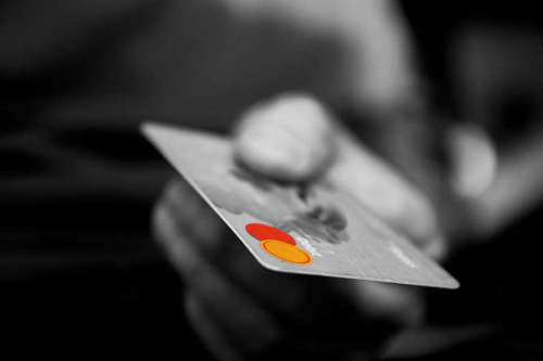 paying-in-store black and white close-up of a hand holding a credit card
