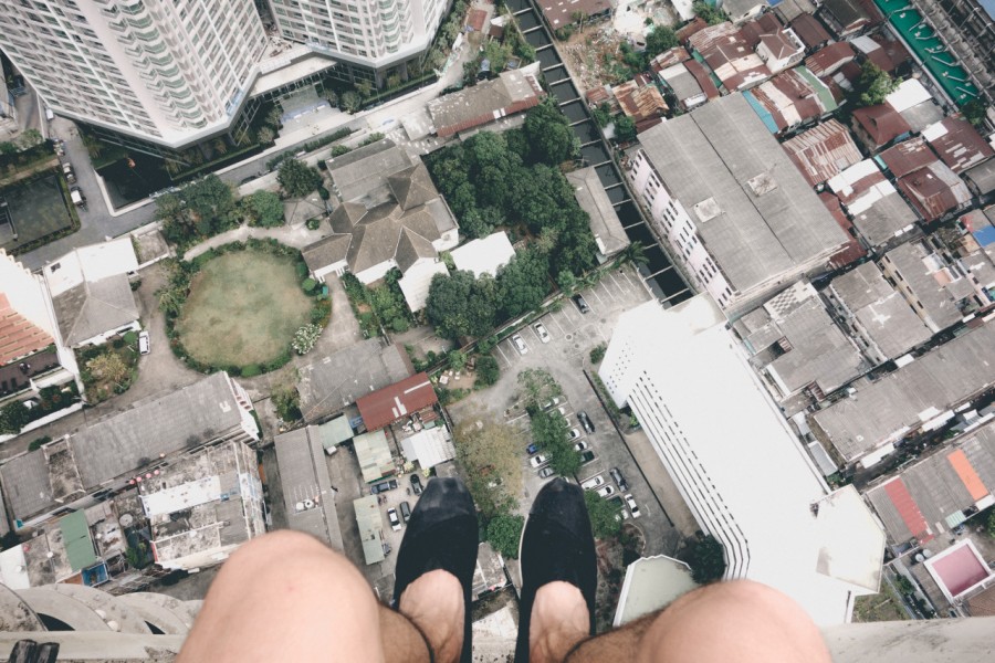 one person, people, man, shoe, shoes, boldness, daring, danger, edge, cornice, adventure, excitement, adrenaline, city, urban, from above, seated, sandals, cliff,